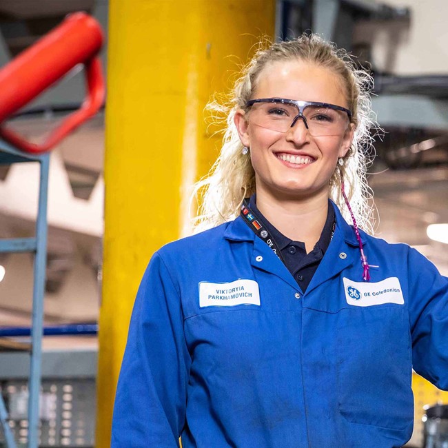 Young female apprentice smiling in factory