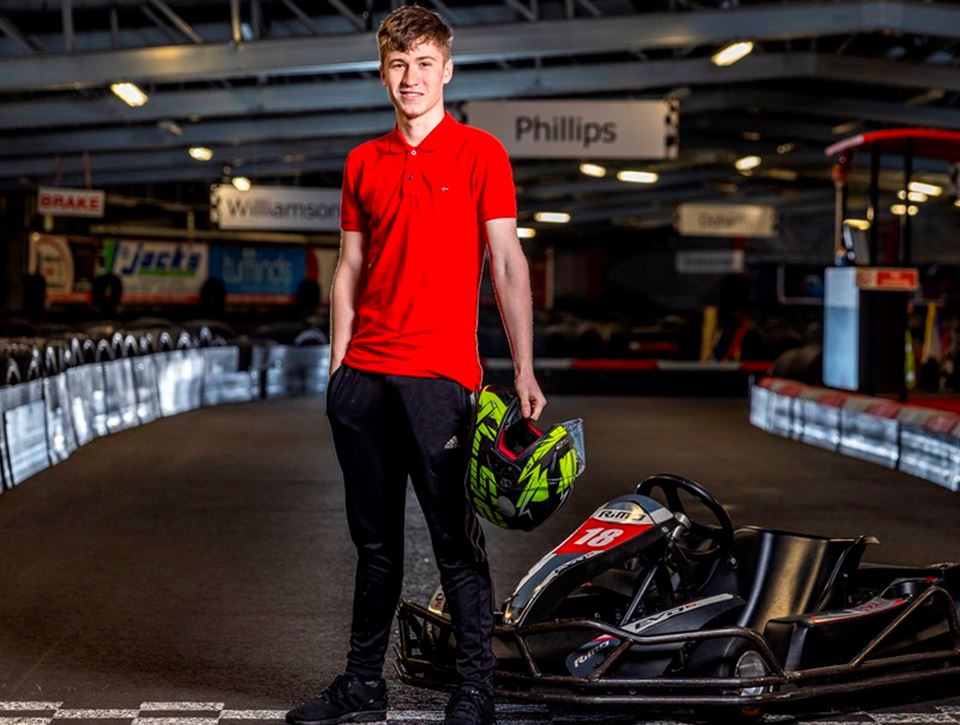 Young apprentice standing in front of a karting racetrack
