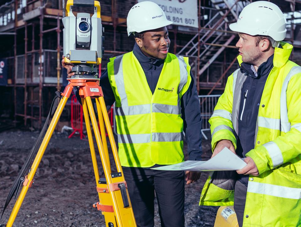 Two men on a construction site with a camera 