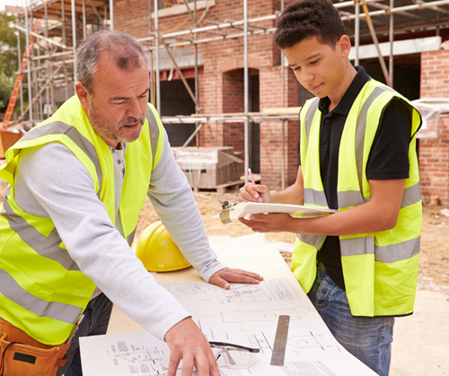 Young man working with manager at a set of construction drawings