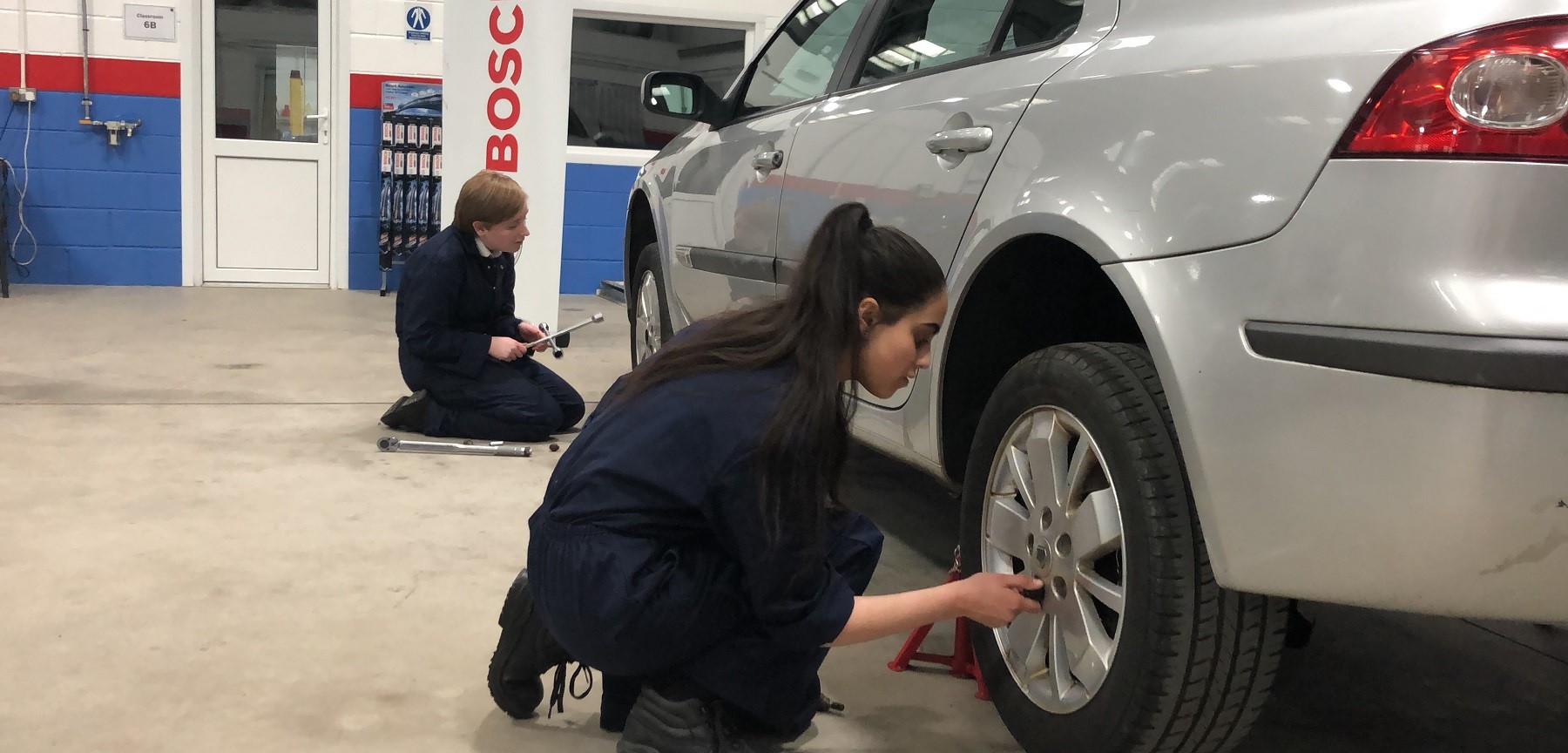 Two young people working on a car 