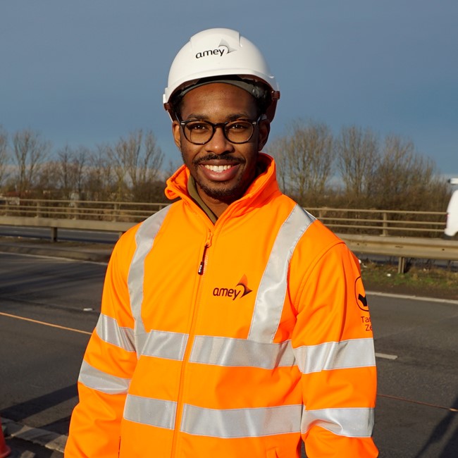 A male apprentice in high vis vest looking at camera