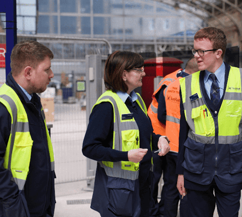 Apprentice talking to colleagues at train station